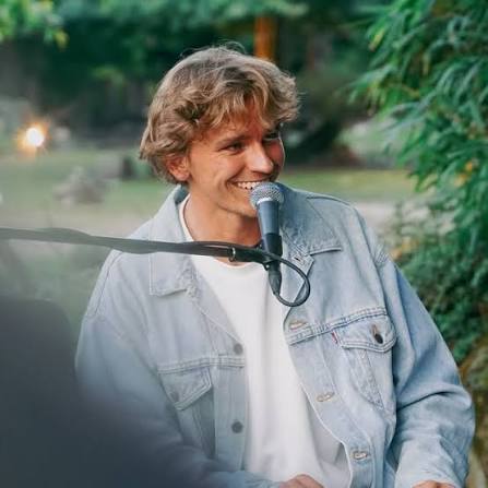 Andre Fischer mit Mikrofon, lächelnd im Garten